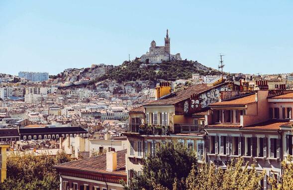 Vue sur Notre Dame de la garde depuis une colline avec la ville au premier plan